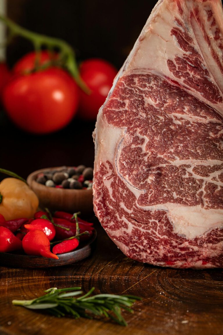 High-quality marbled raw meat with fresh vegetables on a rustic wooden board.